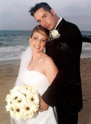 A bride and groom posing for a picture on the beach.