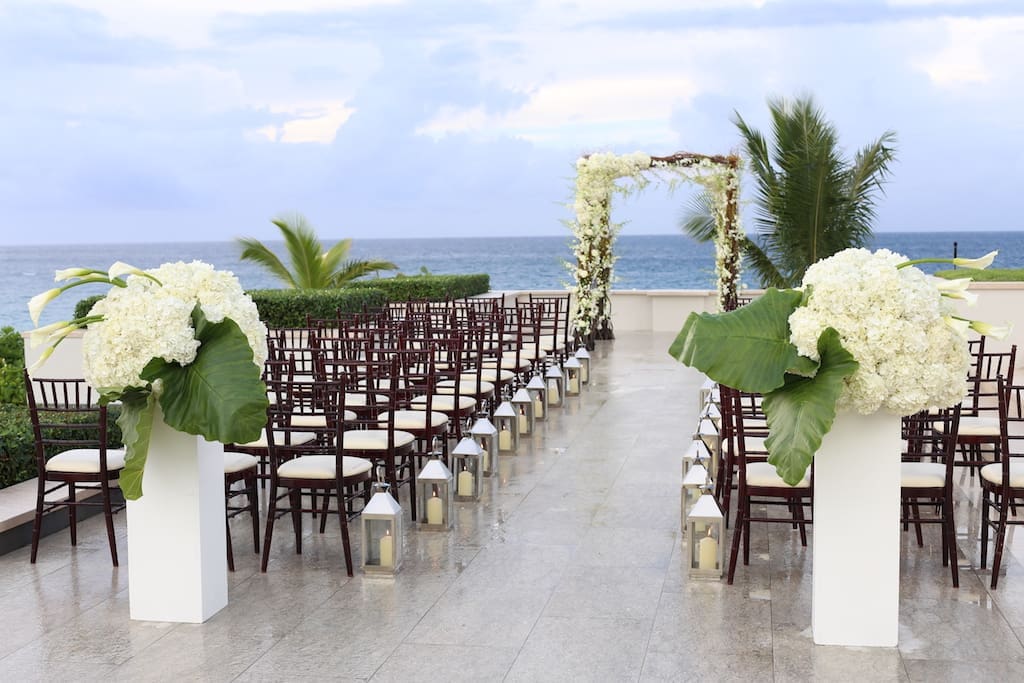 An outdoor wedding ceremony set up with white chairs and flowers.